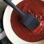 white bowl of barbecue sauce with black pastry brush on a black and white checked cloth.