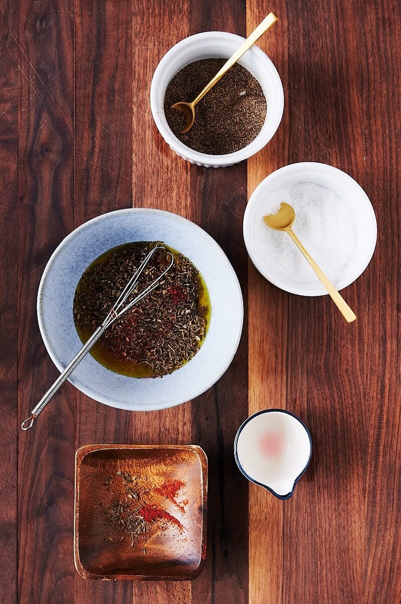 wooden cutting board with bowls containing salad dressing ingredients for tomato tart.