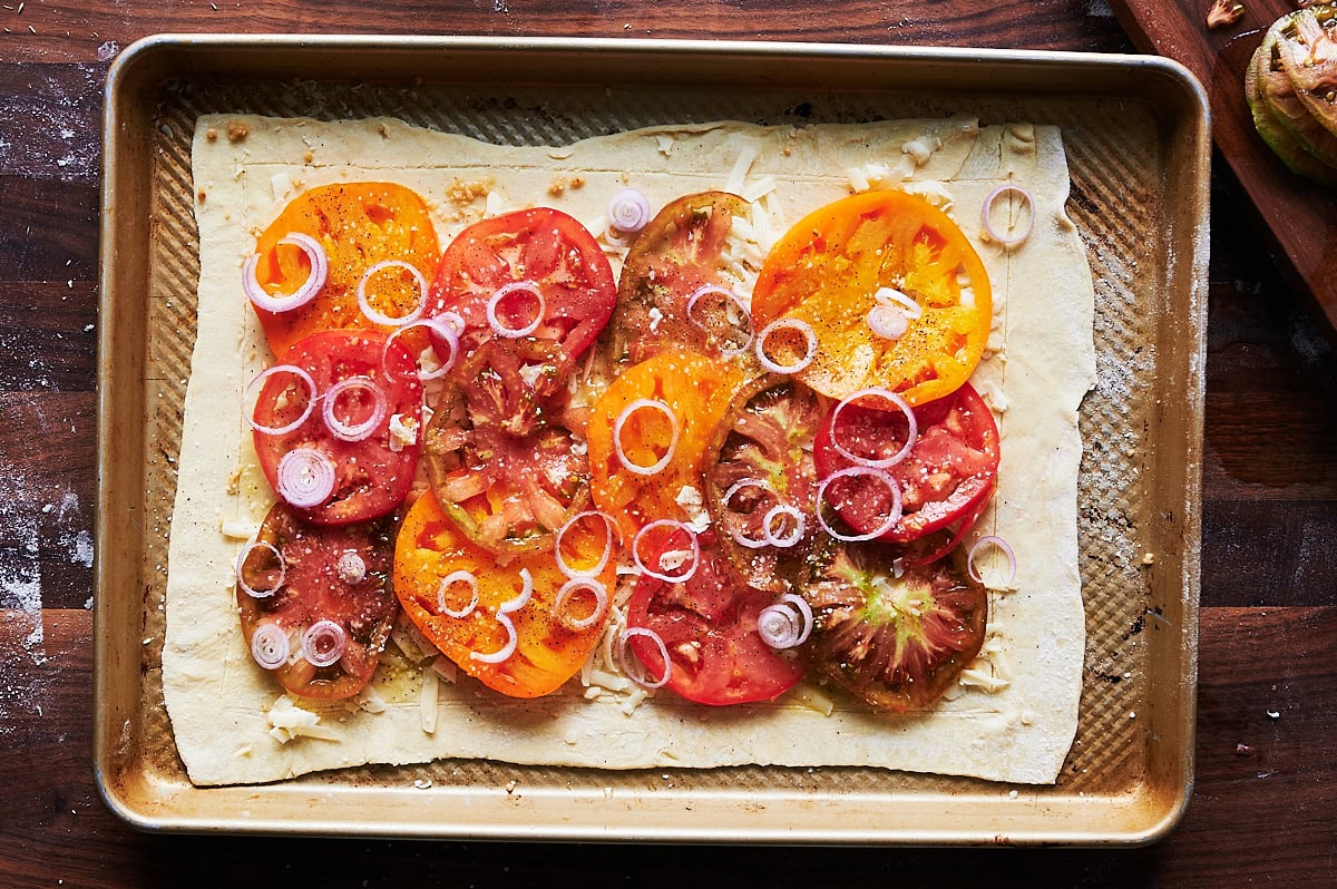 assembled tomato tart sprinkled with shallots on puff pastry.
