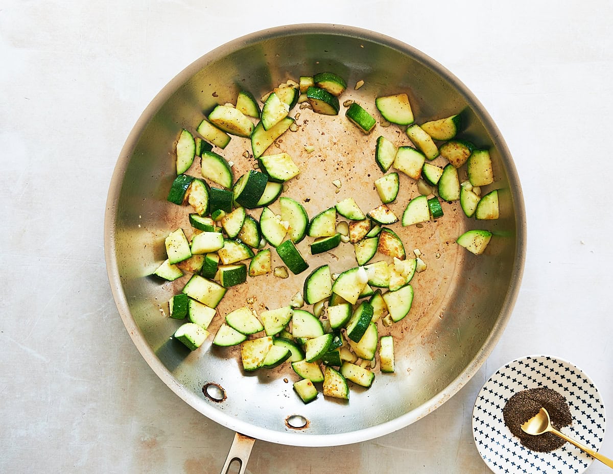 Second step in sauteed zucchini cooking process adding garlic