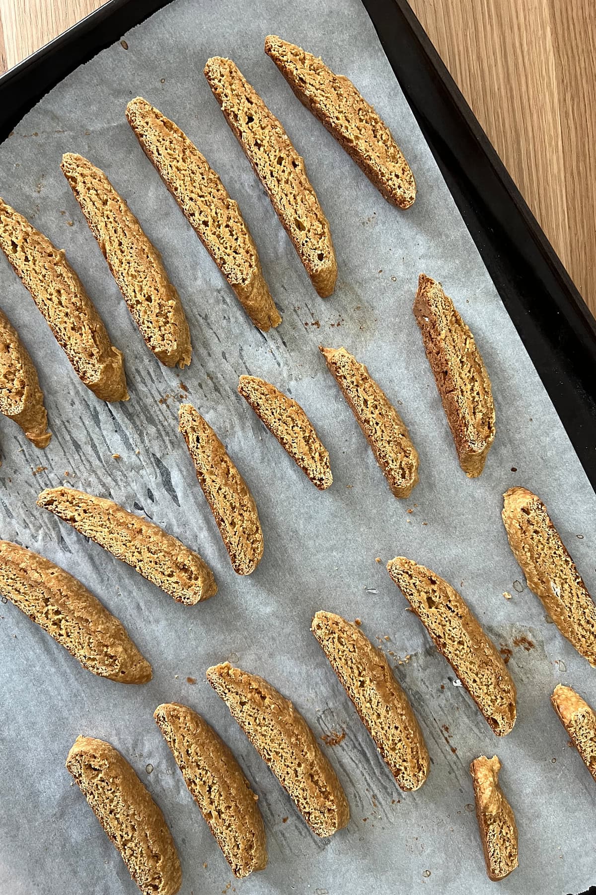 Sliced baked biscotti ready for second bake on parchment sheet pan.