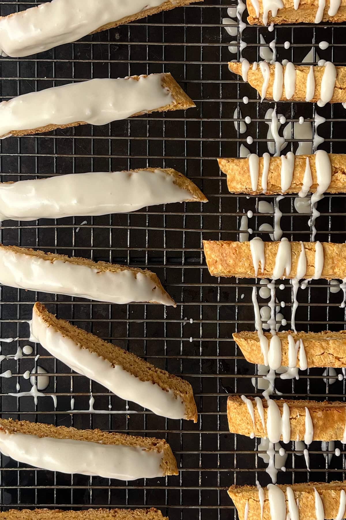 Frosting drizzled standing pumpkin biscotti on black wire rack