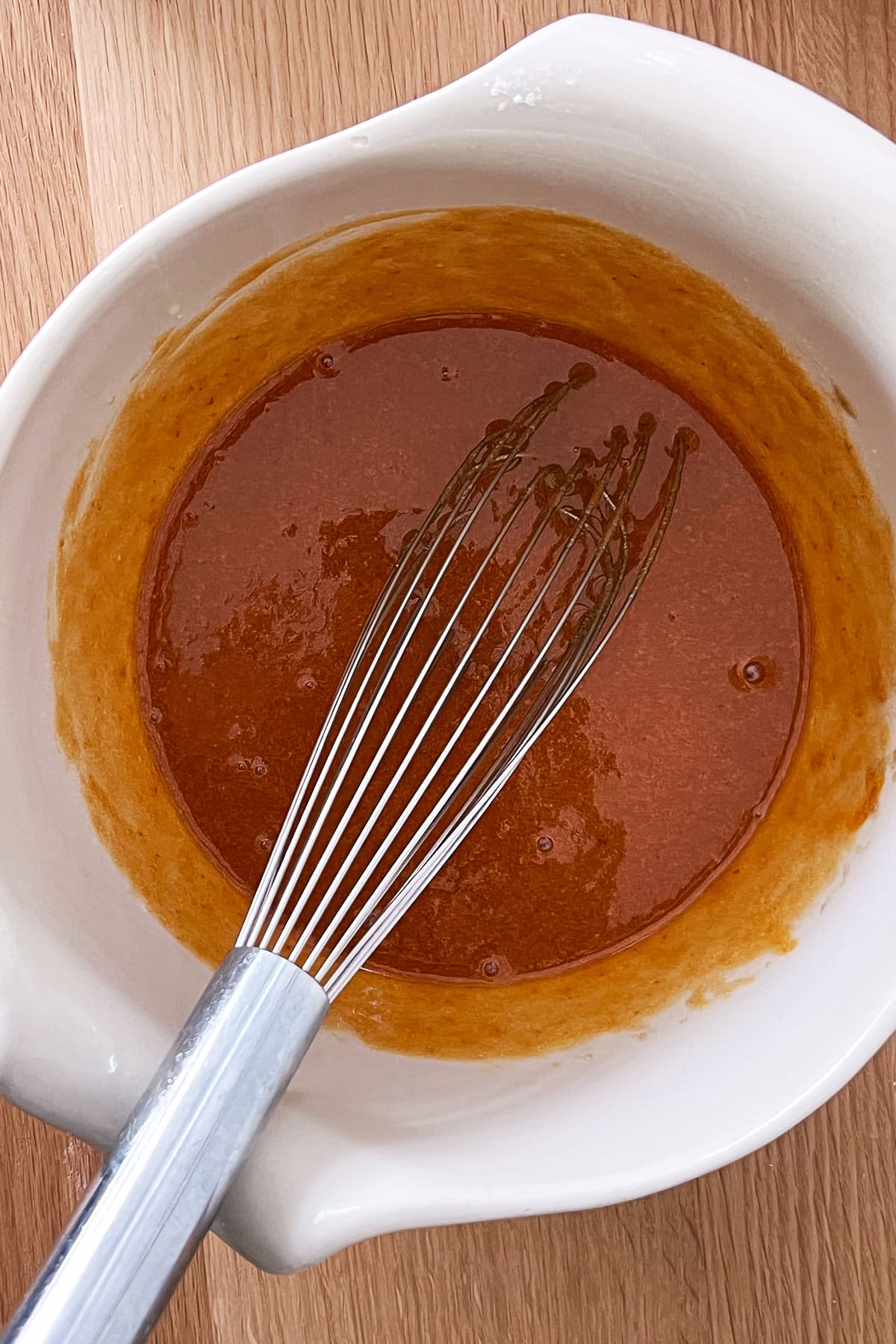 White bowl with whisked pumpkin and sugar mixture.