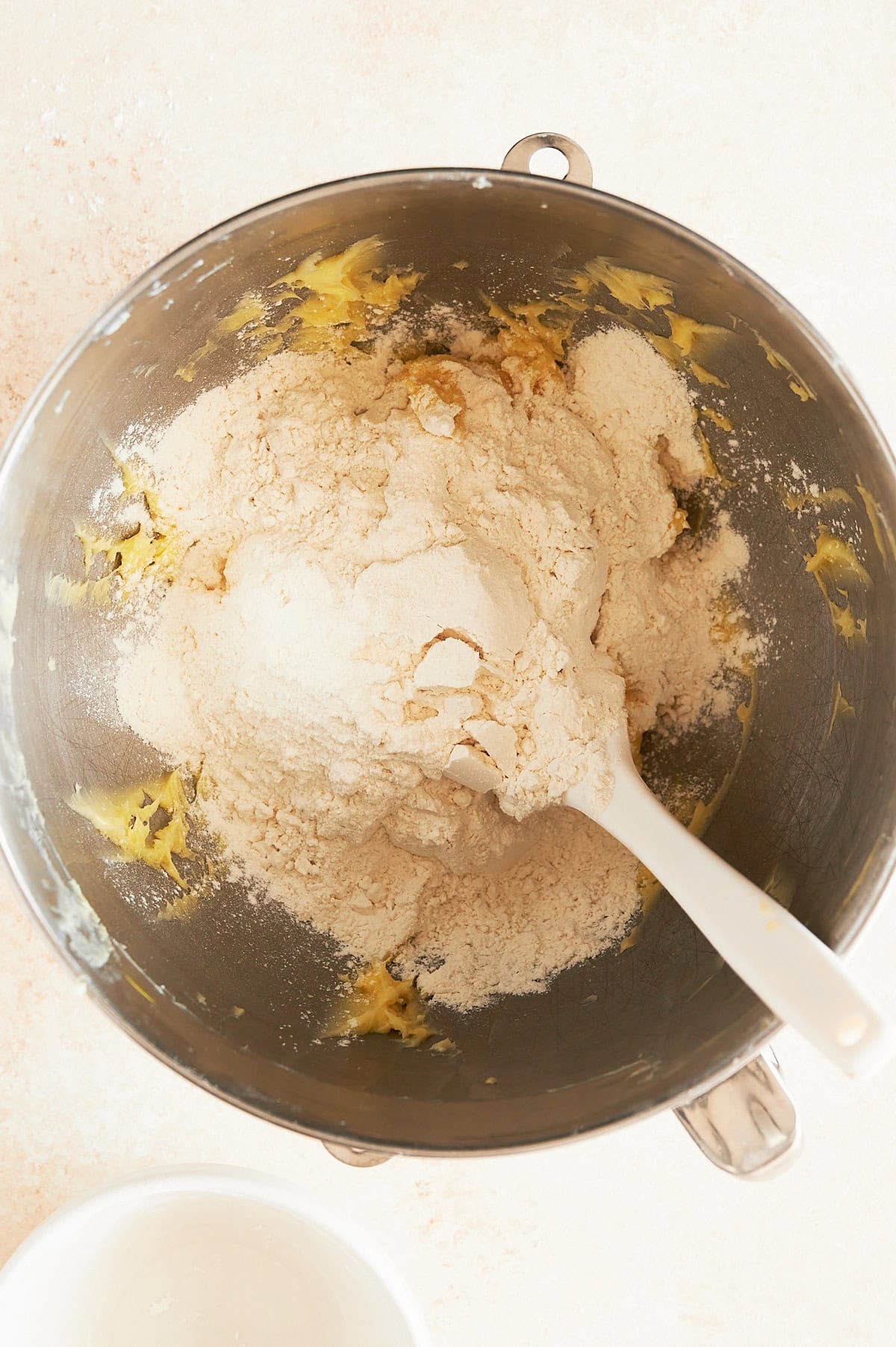 Mixing bowl with dry ingredients being added to butter mix for butter cookies.