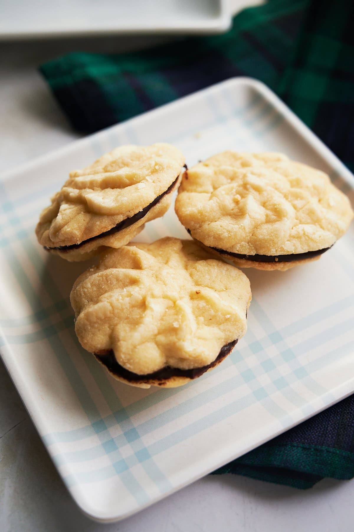blue and white plaid plate of chocolate ganache sandwich butter cookies.