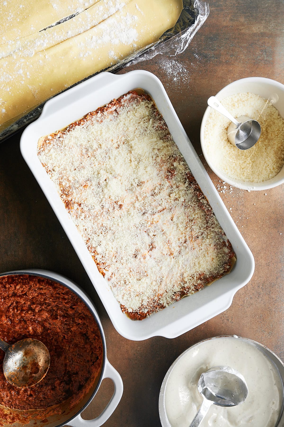 White pan of the second layers of lasagna Bolognese topped with parmesan cheese.