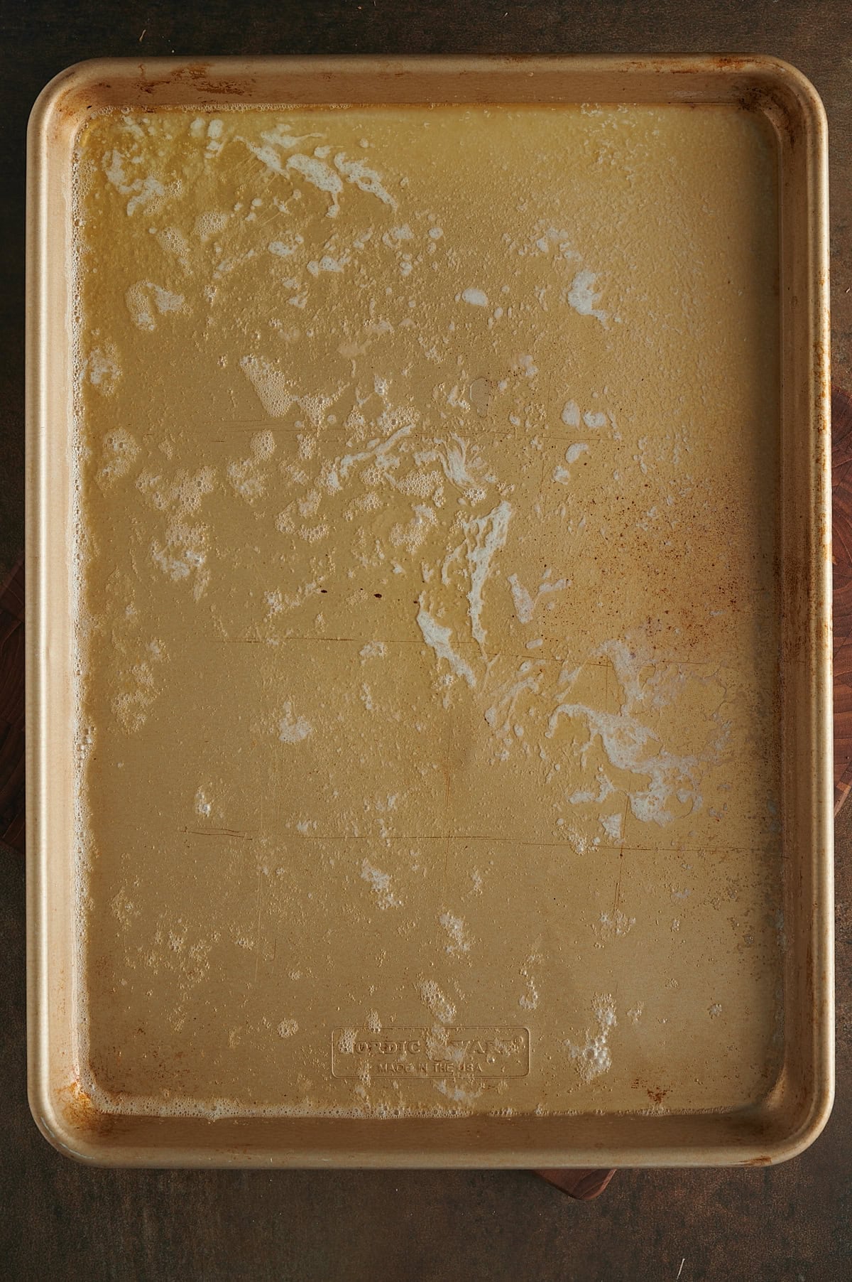 Gold sheet pan with foaming melted butter for roasted sweet potatoes.