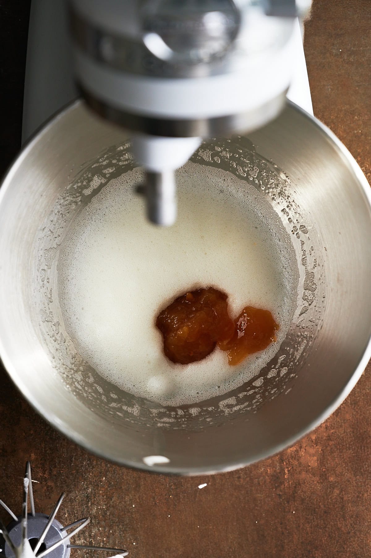 Stainless mixing bowl with apricot jam ready to be folded into whipped egg whites.