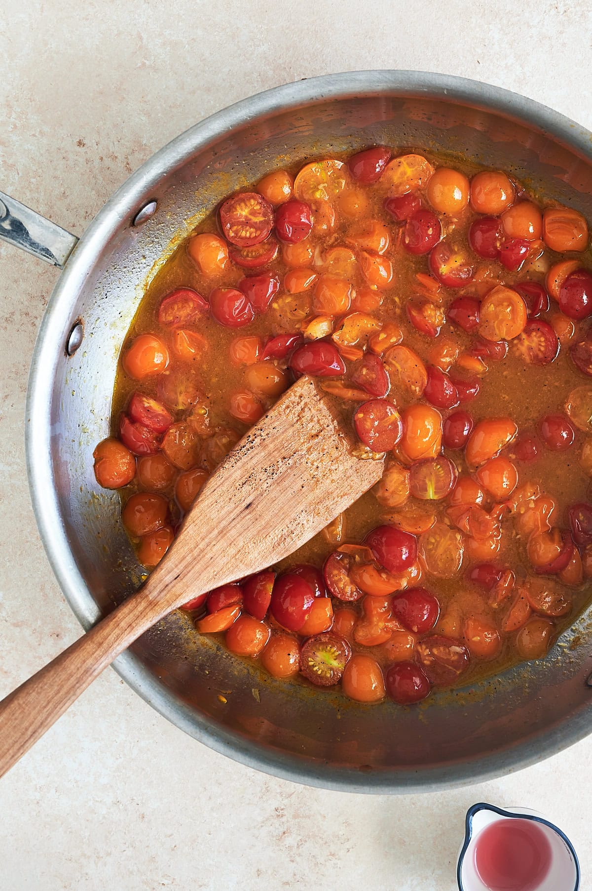 Finished pan of garlic tomato sauce in a stainless skillet with a wooden paddle.