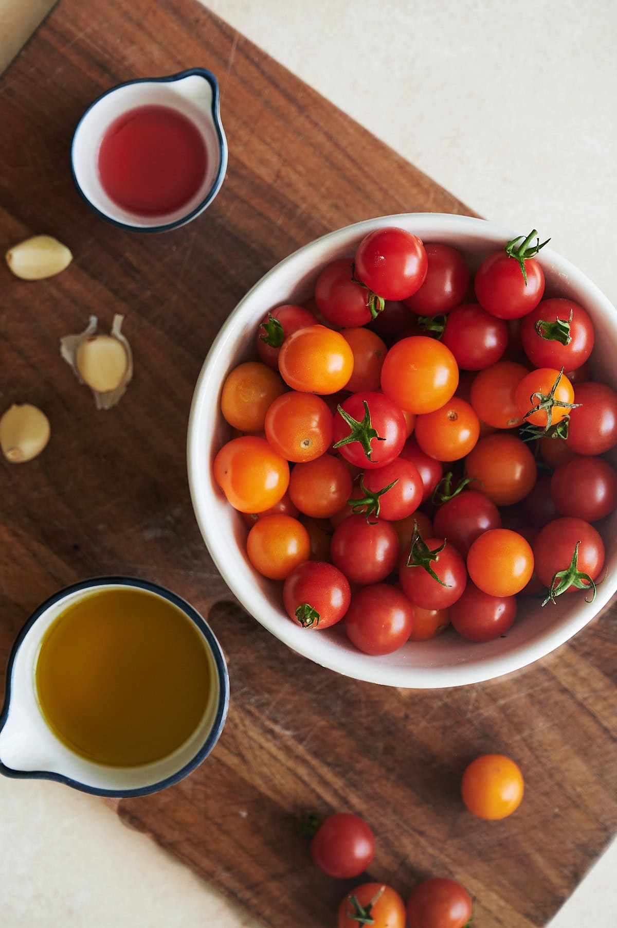 Ingredients for sugo all'aglione or garlic tomato sauce on a wooden cutting board.