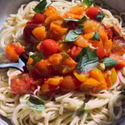 Finished bowl of pasta with garlic tomato sauce and a black fork in it.