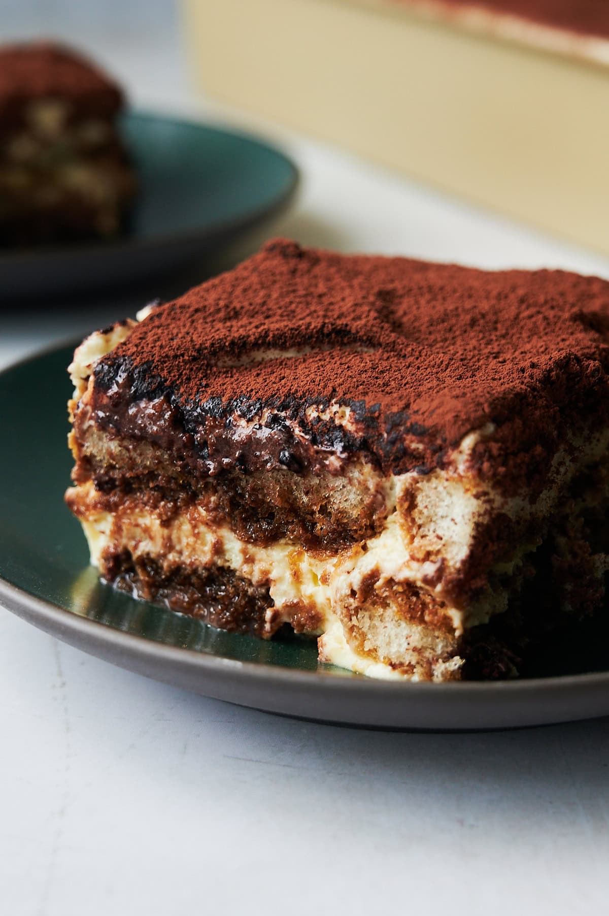 Close up piece of tiramisu on a green plate.