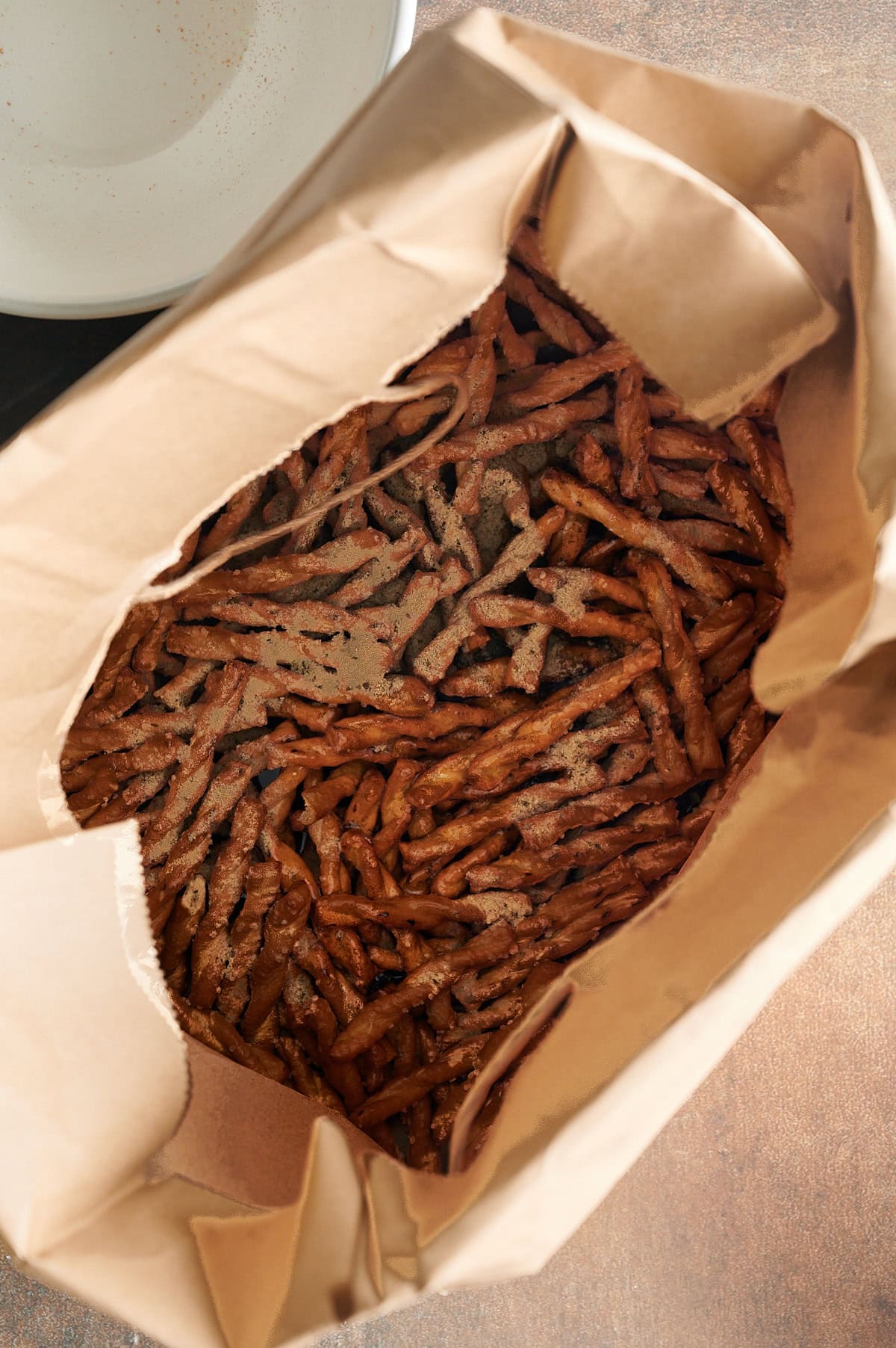 Brown bag with butter braid pretzels sprinkled with parmesan garlic and topped with oil.