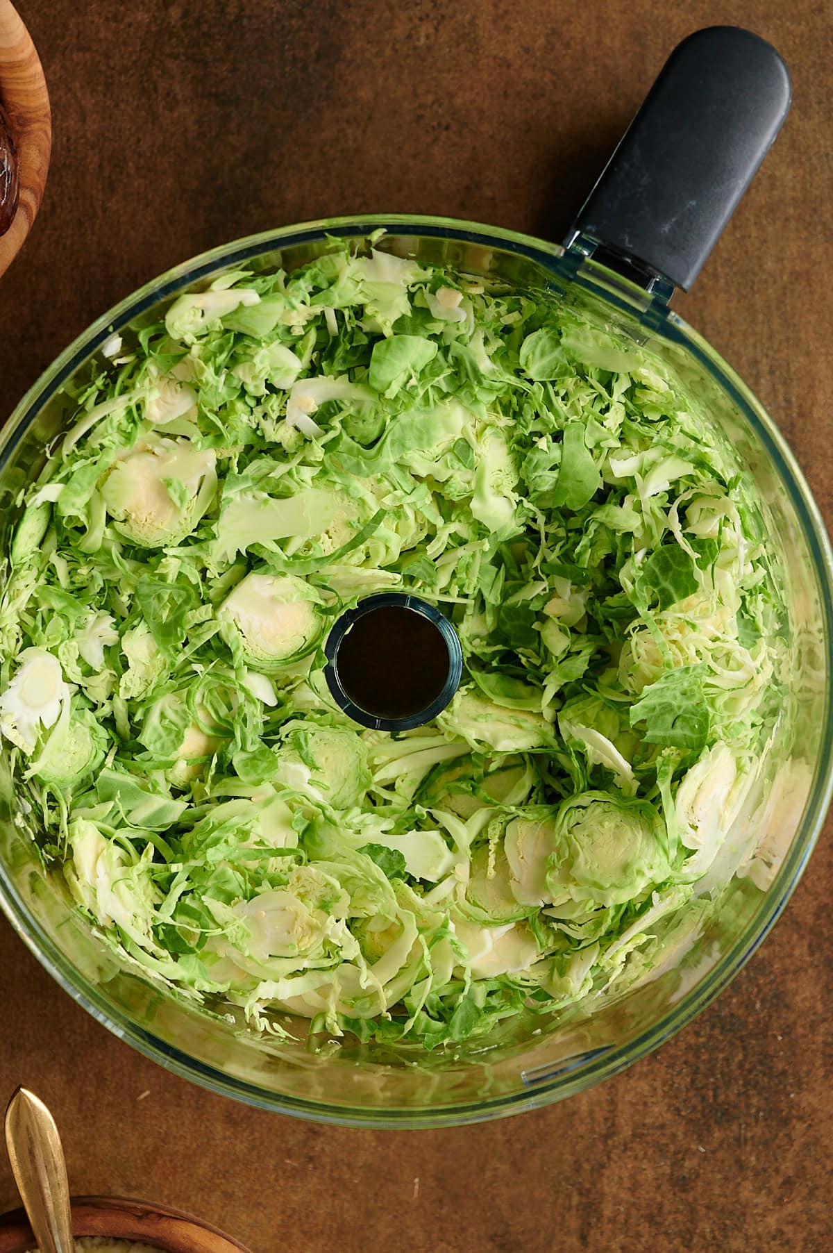 Food processor bowl of Brussels sprouts shaved for salad.