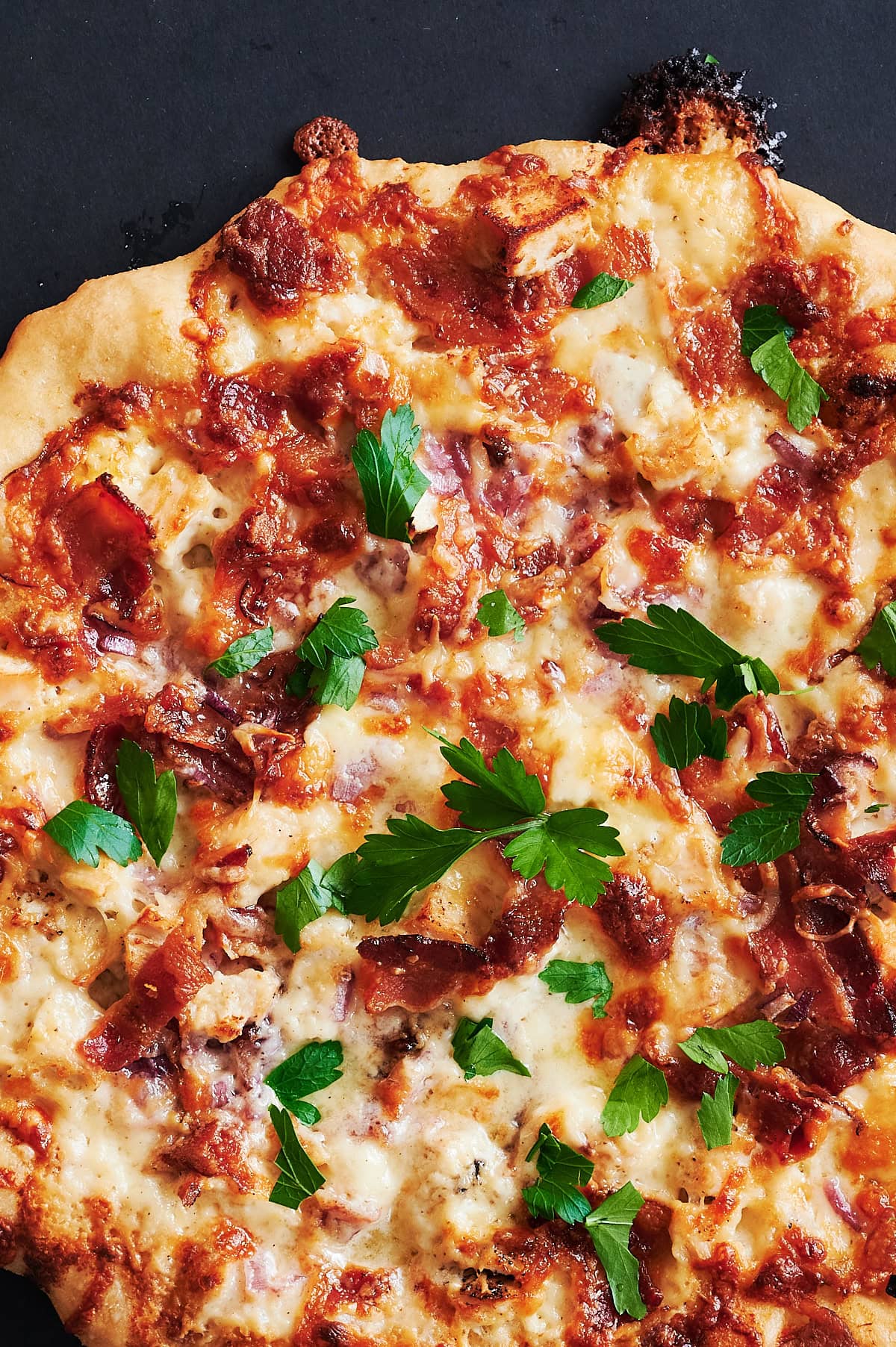 Close up of baked cheesy chicken bacon pizza.