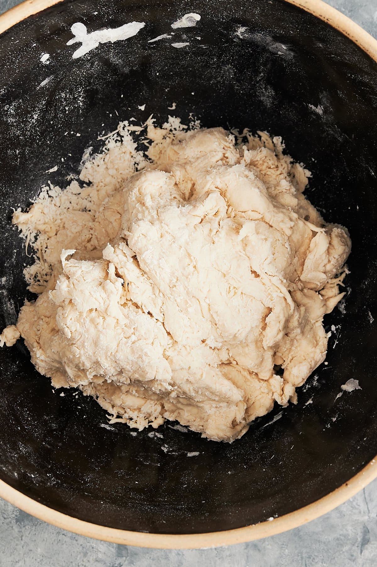 Close up of black bowl with just mixed pizza dough.