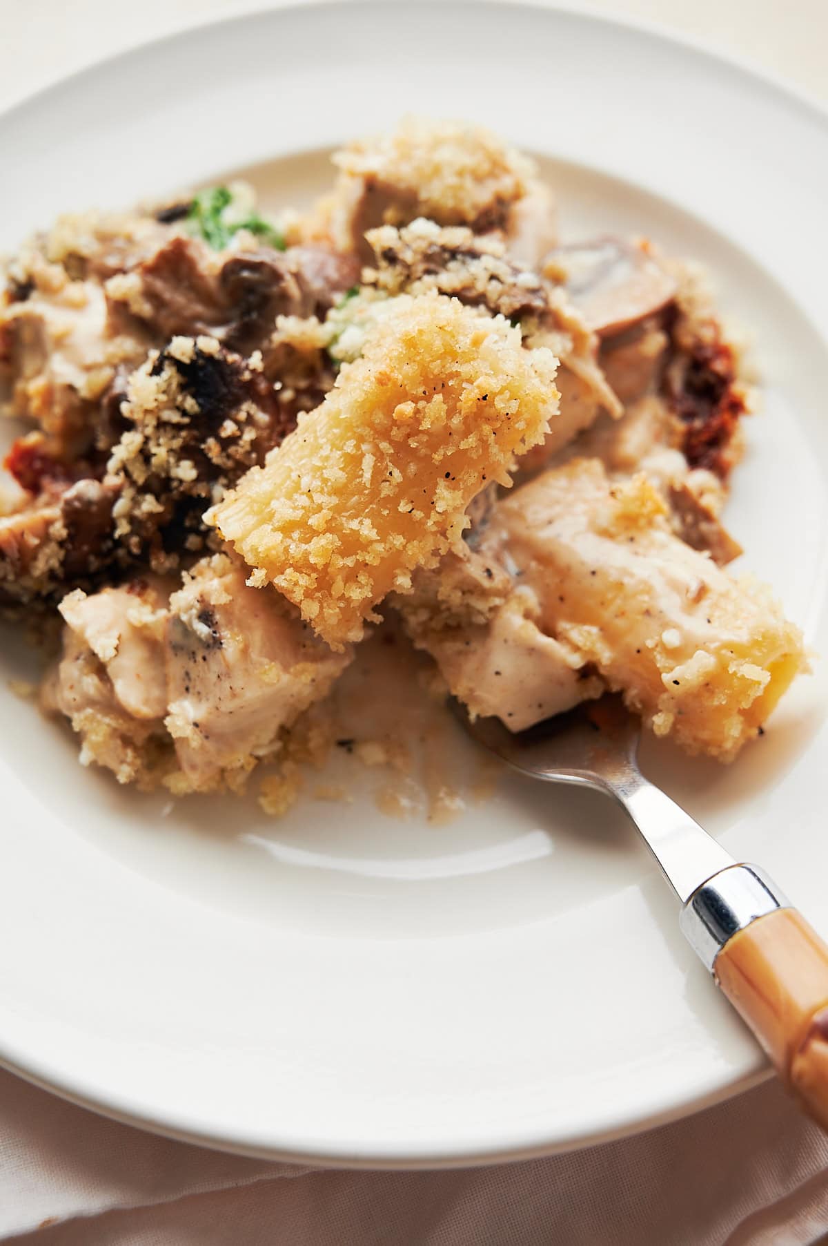 White plate of baked and crispy breadcrumb rigatoni with creamy chicken and mushrooms.