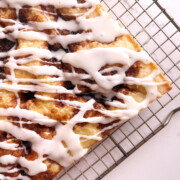 Baked cinnamon roll focaccia on a cooling rack after being iced.