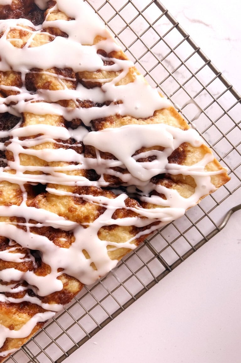 Baked cinnamon roll focaccia on a cooling rack after being iced.
