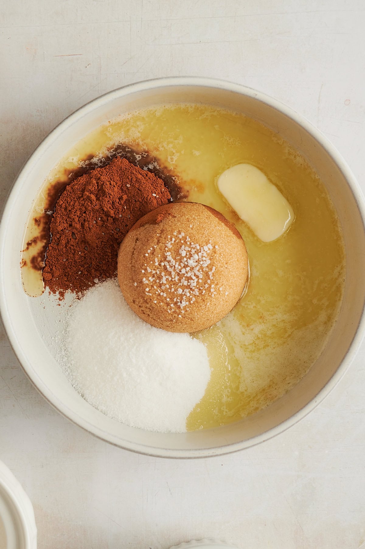 Bowl of melted butter with cup of brown sugar, cinnamon, sugar, and salt for icing for focaccia bread.