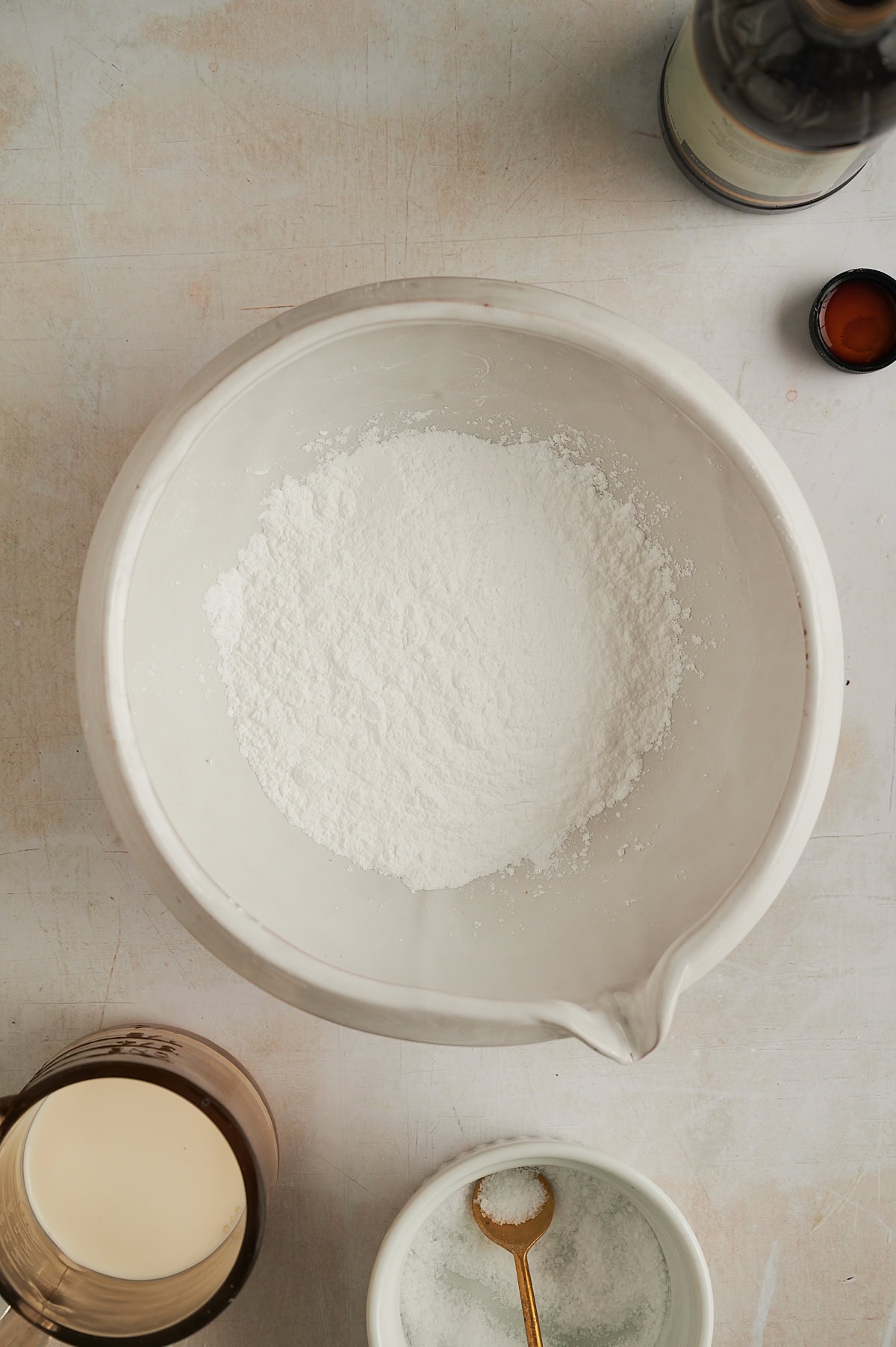 Powdered sugar in white bowl with vanilla, milk and salt for cinnamon focaccia bread.