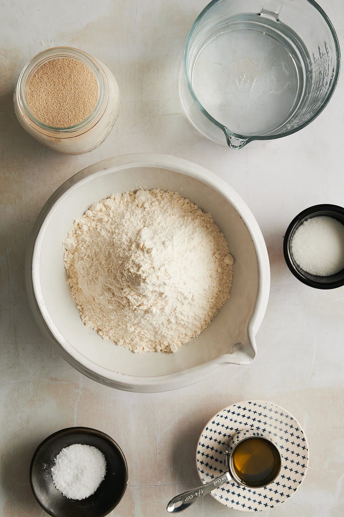 Bowls of ingredients for cinnamon roll focaccia bread including flour, yeast, salt, sugar and oil.