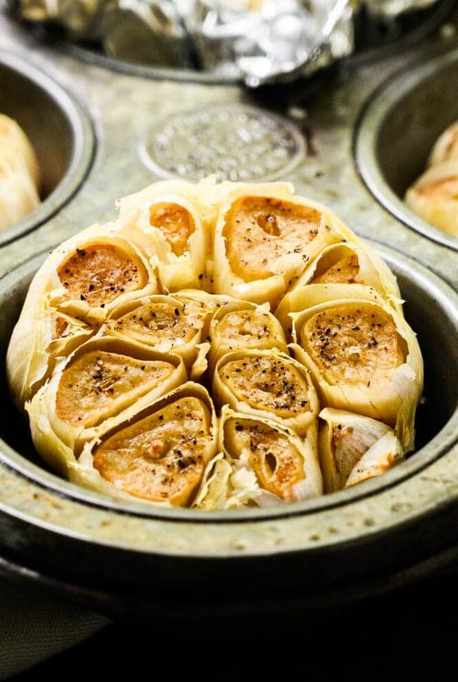whole heads of roasted garlic in a muffin tin.