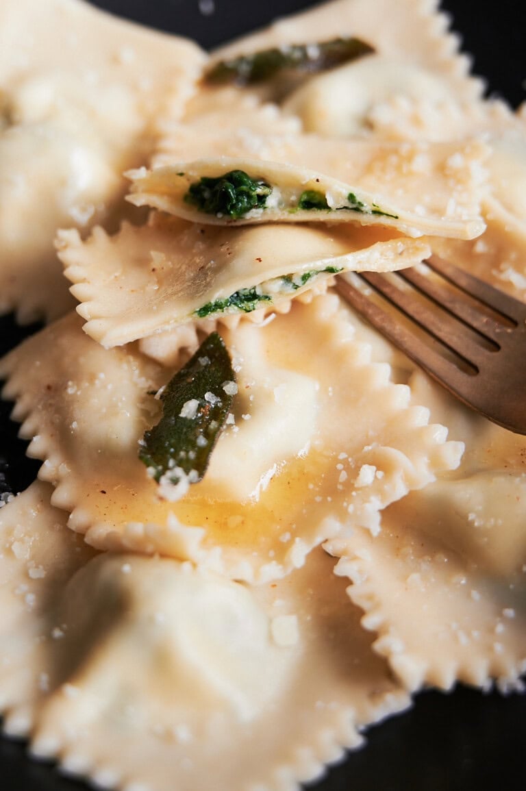 Parmesan cheese topped spinach and cheese ravioli drizzled with butter sauce with sage leaves.