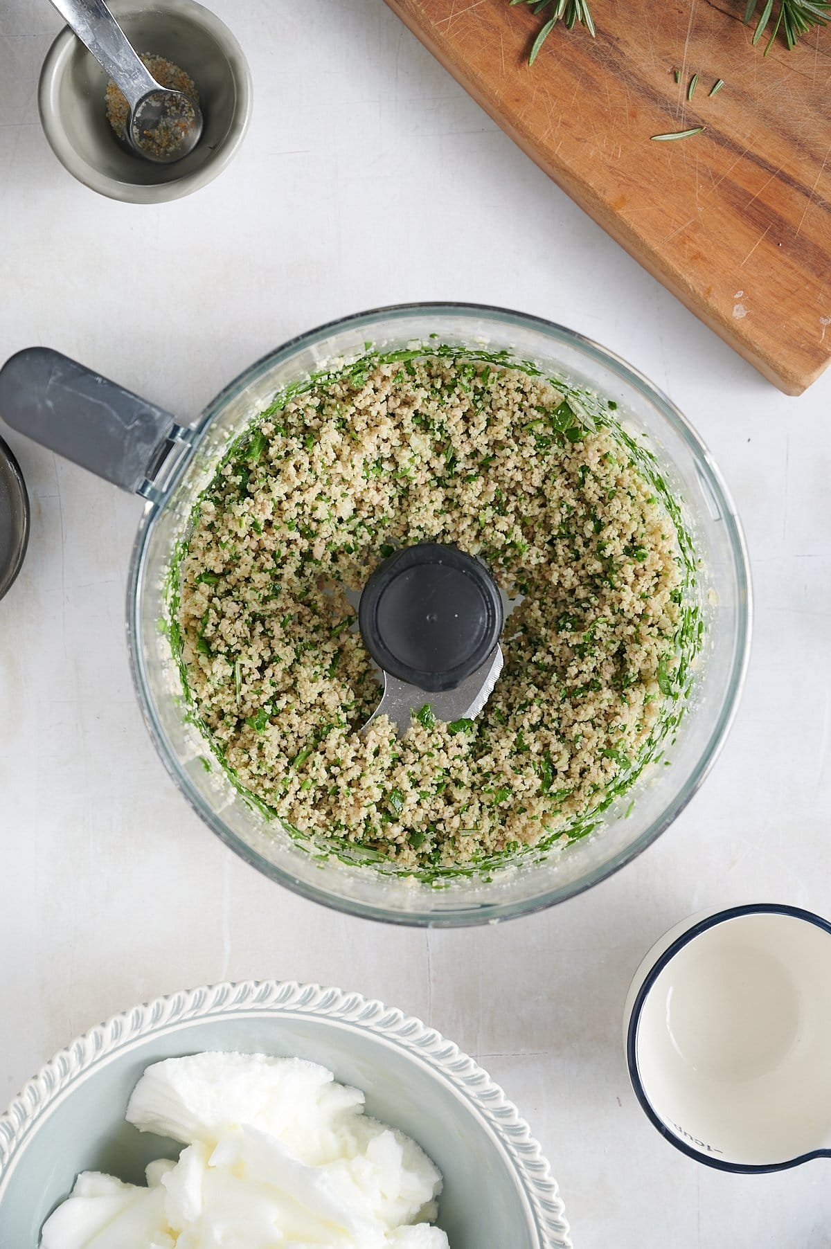 A food processor contains blended chicken ravioli filling with fresh spinach.