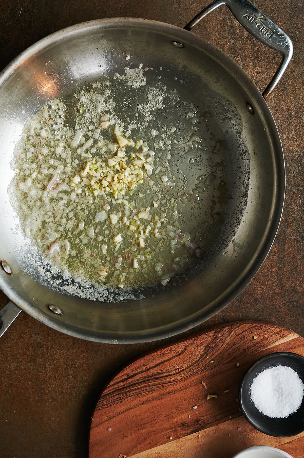 Skillet of onions and garlic being sauteed in butter.