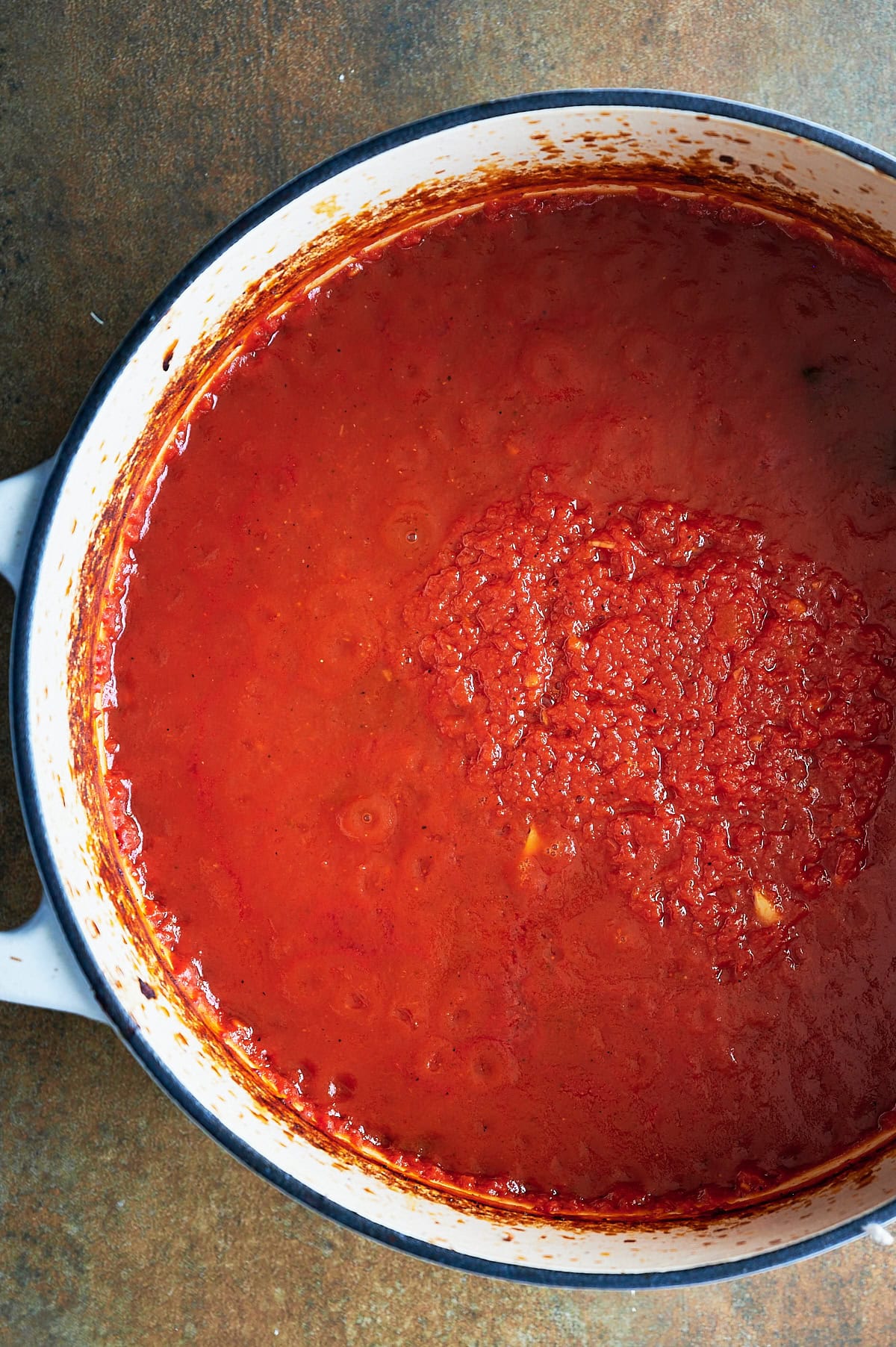 A white pot filled with thick, baked tomato sauce, showing a rich red color