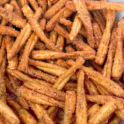A bowl filled with seasoned pretzel sticks, coated with visible spices and arranged closely together.