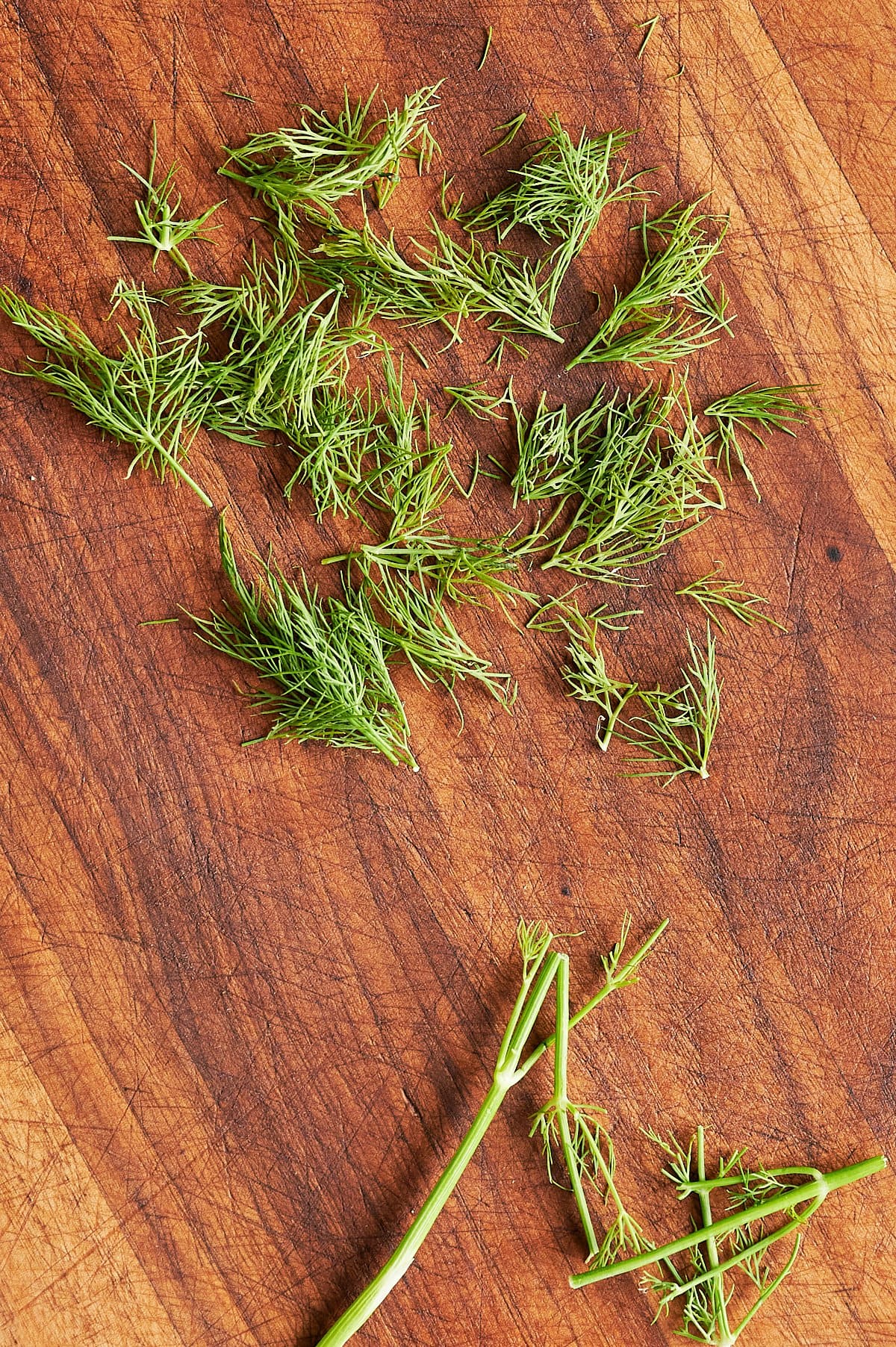 A bunch of fresh dill leaves on a wooden surface.
