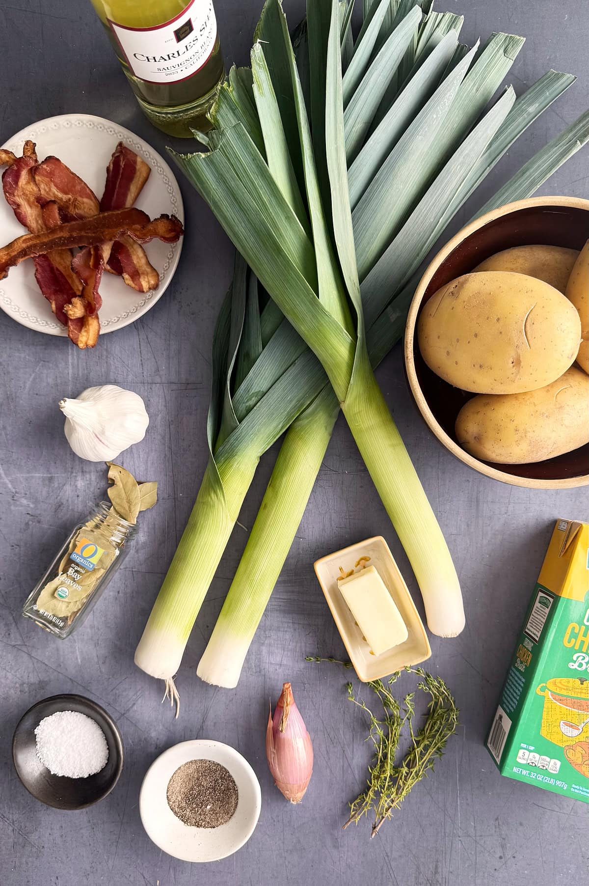 A bunch of leeks and potatoes on a table.