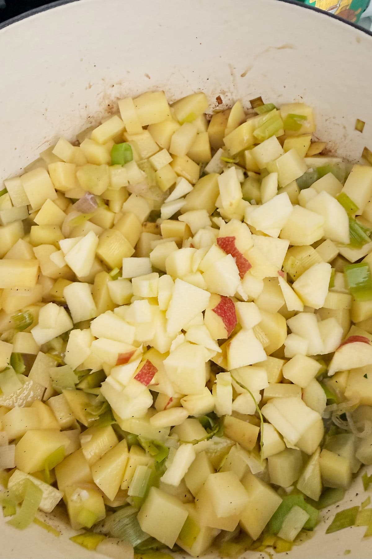 Chopped potatoes, apples, celery, and onions in a large pot, ready for cooking.