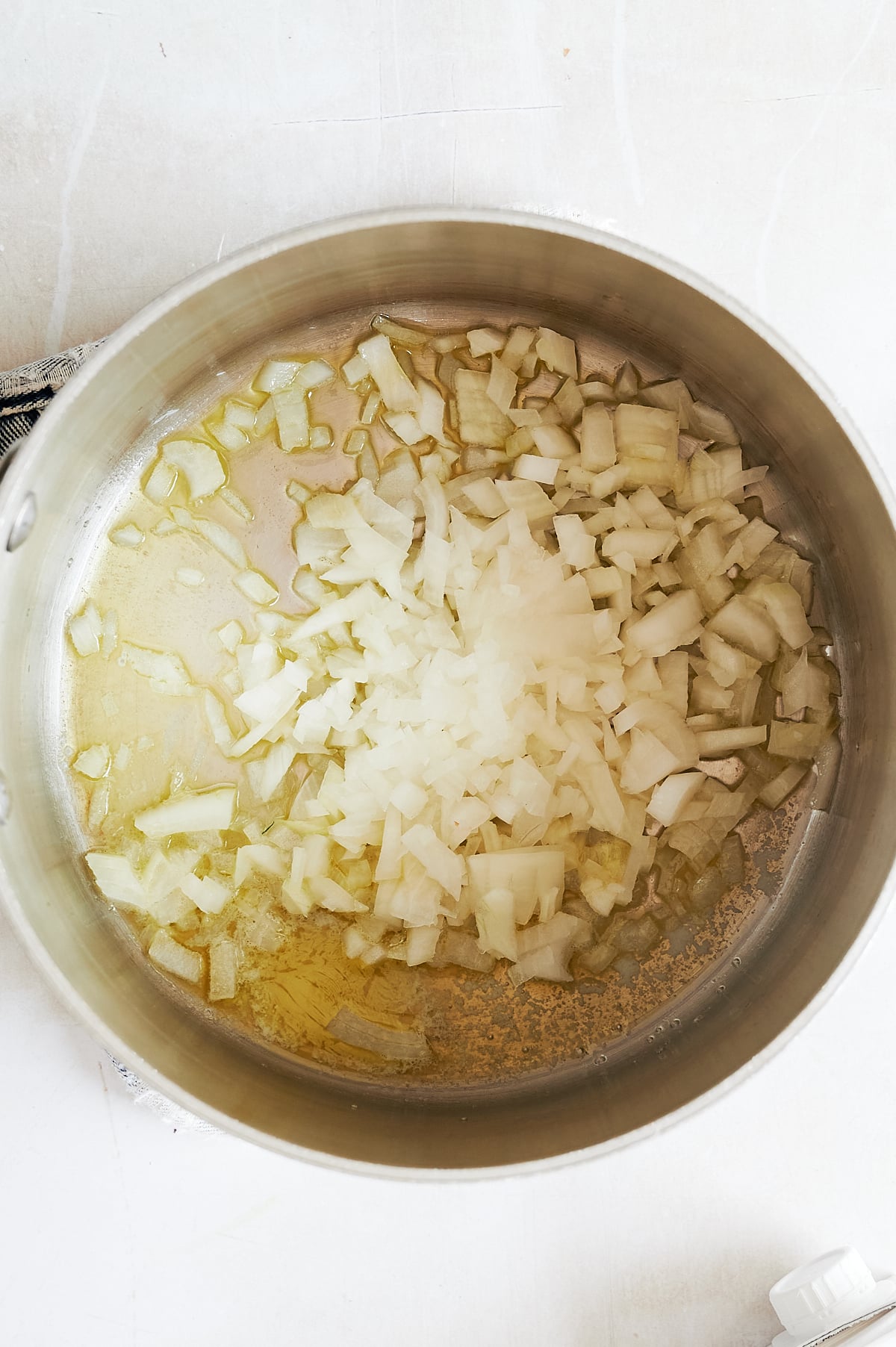 Diced onions sautéing in a sauce with oil and butter.